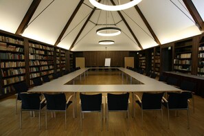 A library with a long table and chairs, wooden bookshelves, and a high ceiling with a cross. - Single Room - Protestant Augustinian Monastery in Erfurt (Erfurt)