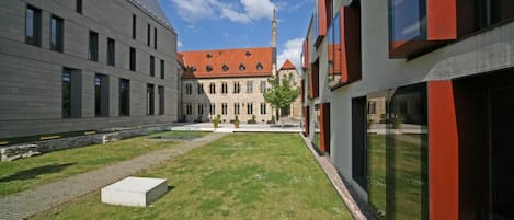 A courtyard with a modern building and a traditional building with a red roof.