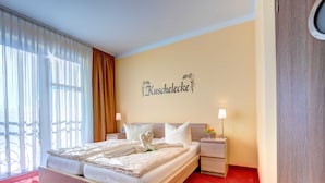 Une chambre d’hôtel avec un grand lit, deux tables de chevet, une moquette rouge et un mur sur lequel est inscrit le nom « Kuschelecke ».