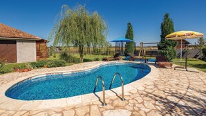 A swimming pool with a stone deck, surrounded by a wooden fence, and a grassy area with trees. - Pet friendly home in Ozalj (Ozalj)