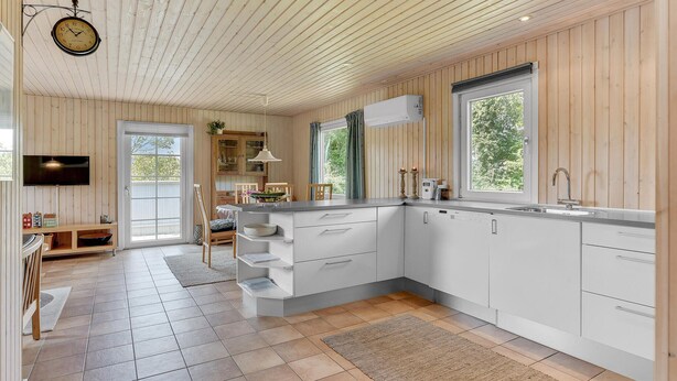 Una cucina moderna con mobili bianchi, forno integrato e un'ampia finestra.