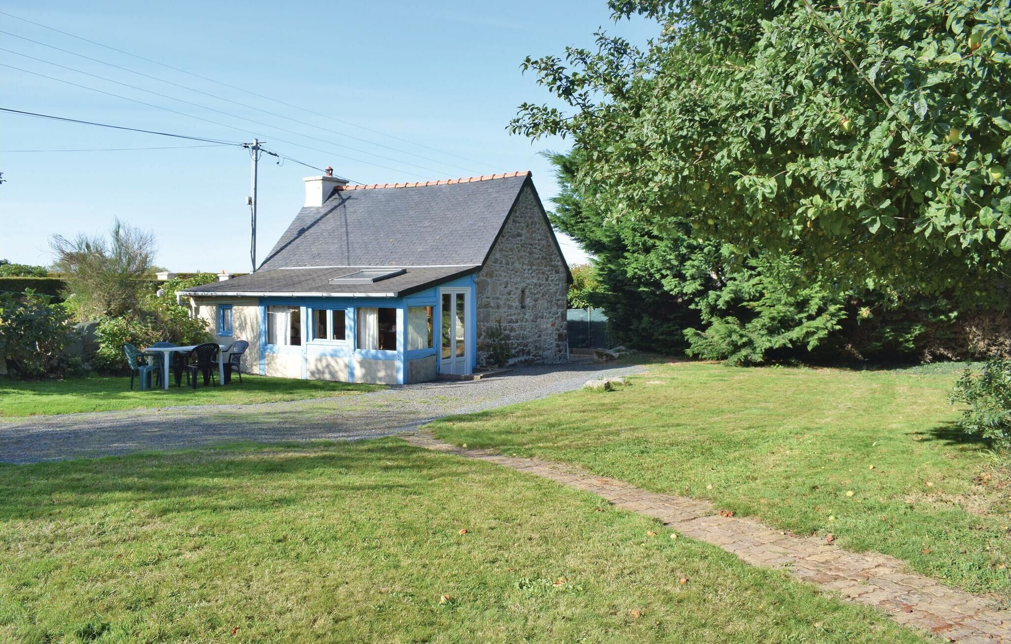 Een stenen huis met schuin dak, een klein terras en een grindpad dat leidt naar een gazon.