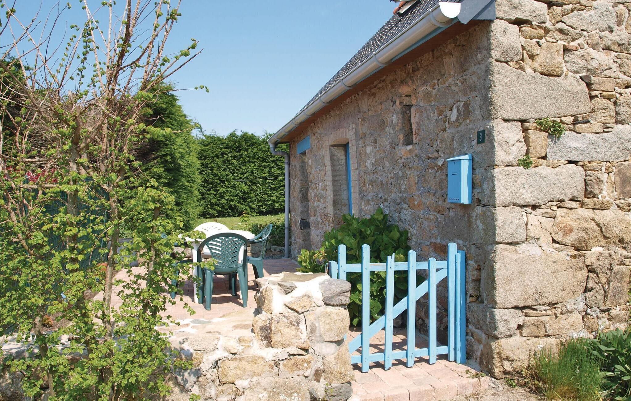 Un bâtiment en pierre avec un portail en métal, un chemin en pierre et une chaise à l’extérieur.