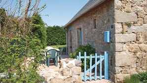A stone building with a metal gate, a stone pathway, and a chair outside. - 1 bedroom beautiful home in Pleubian (Pleubian)