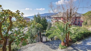 A hillside residential area with stone pathways, lush greenery, and houses with balconies overlooking a body of water and distant mountains. - Nice apartment in Rapallo GE with swimming pool (Rapallo GE)