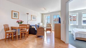 Une pièce spacieuse comprenant une table à manger en bois, des chaises, un canapé et un lit.