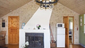 Une pièce chaleureuse avec une cheminée, des murs en bois, un ventilateur de plafond et un four à micro-ondes.