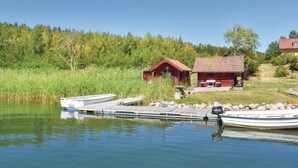 Un chalet au bord du lac, doté d’un quai, et entouré d’une forêt dense.
