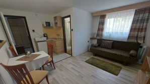 A compact living space with a dining area, kitchenette, and a sofa. - Holiday apartment with large garden and internet (Balatonföldvár)