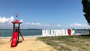 A beach with a lifeguard tower, a large sign reading "BALATONERODAR", and a clear view of the sea. - Holiday apartment with large garden and internet (Balatonföldvár)