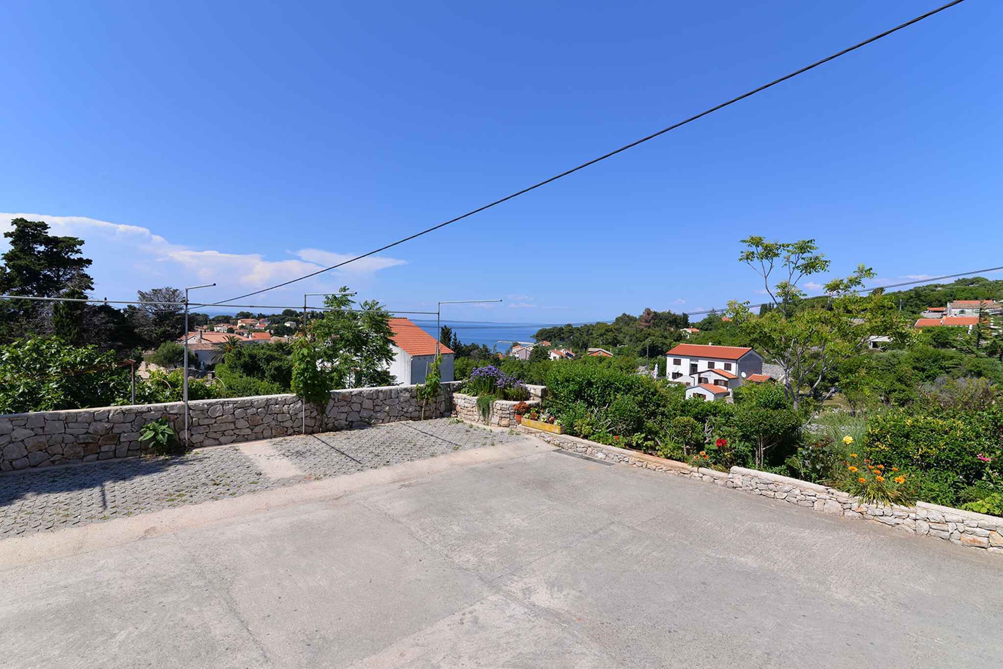A residential area with stone walls, houses with red roofs, and a clear blue sky.