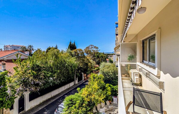 A narrow street flanked by lush greenery and buildings with balconies. - Cozy apartment in Juan-les-Pins (Juan-les-Pins)