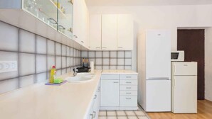 Een moderne keuken met witte kastjes, een spoelbak, een magnetron en een koelkast.