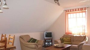 A cozy living room with a sofa, armchair, and dining table.
