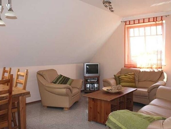 A cozy living room with a sofa, armchair, and dining table. - Apartment 2 (1st floor) - Landhaus Storchenblick **** WE-20160 (Putbus)