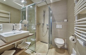 Une salle de bain moderne avec une douche à parois de verre, un lavabo avec un miroir et des toilettes.