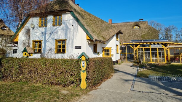 A traditional building with a thatched roof, a sign indicating room number 9, and a small adjacent structure with yellow trim. - 1 - "Up'n Hoff", Germany (Middelhagen)