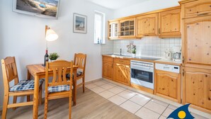 A kitchen with wooden cabinets, a dining table with chairs, a lamp, and a window.
