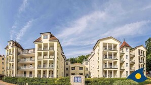 A multi-story hotel with balconies, a central entrance, and a clear sky.