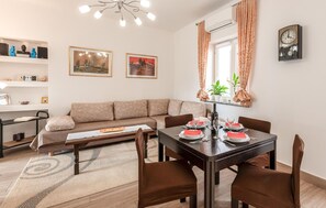 Un salon moderne comprenant un canapé, une table à manger, des chaises, une table basse, des œuvres d’art et une horloge murale.