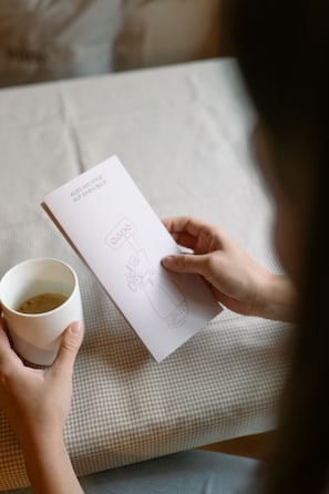 Una persona sosteniendo un sobre blanco con texto y una taza de café.