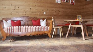 Ein Holzblockhaus-Interieur mit einer Couch, einem Holztisch und Stühlen.