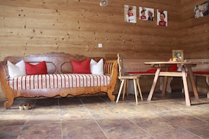 A wooden cabin interior with a sofa, a wooden table, and chairs.