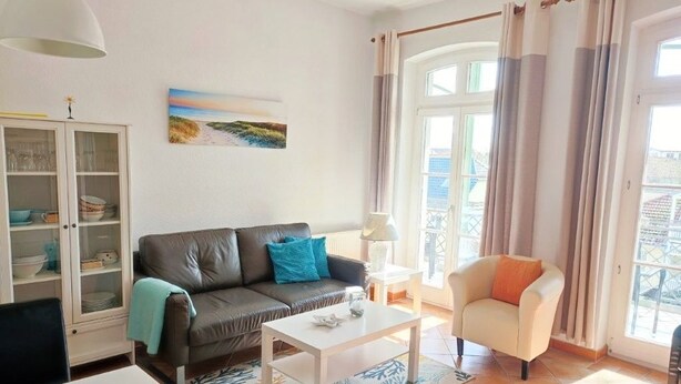 Uma sala de estar com sofá, poltrona, mesa de centro e um armário.