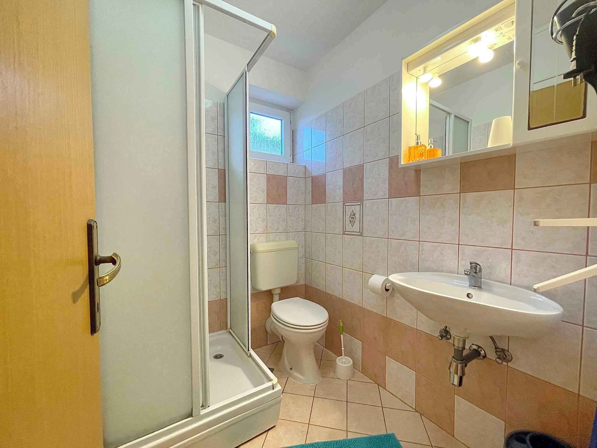 Ein Badezimmer mit Dusche, Toilette, Waschbecken und Spiegel.