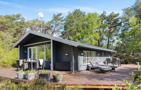 A modern cabin with a deck, outdoor seating, and a satellite dish.