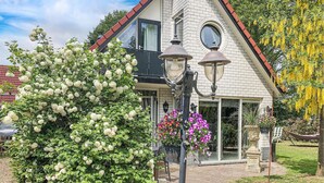 Une maison avec une façade en briques, un toit rouge et une grande fenêtre.