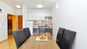 A dining area with a wooden table, black chairs, and a fruit bowl.