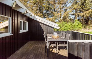 A wooden deck with a table and chairs, a window, and a view of trees and greenery. - 3 bedroom beautiful home in Hjørring (Hjørring)