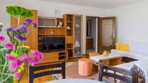 A cozy living room with a TV, wooden furniture, and a sofa. - Holiday apartment with garden and barbecue (Crikvenica)