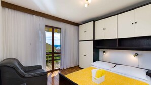 A bedroom with a bed, a chair, and a view of the outdoors. - Holiday apartment with garden and barbecue (Crikvenica)