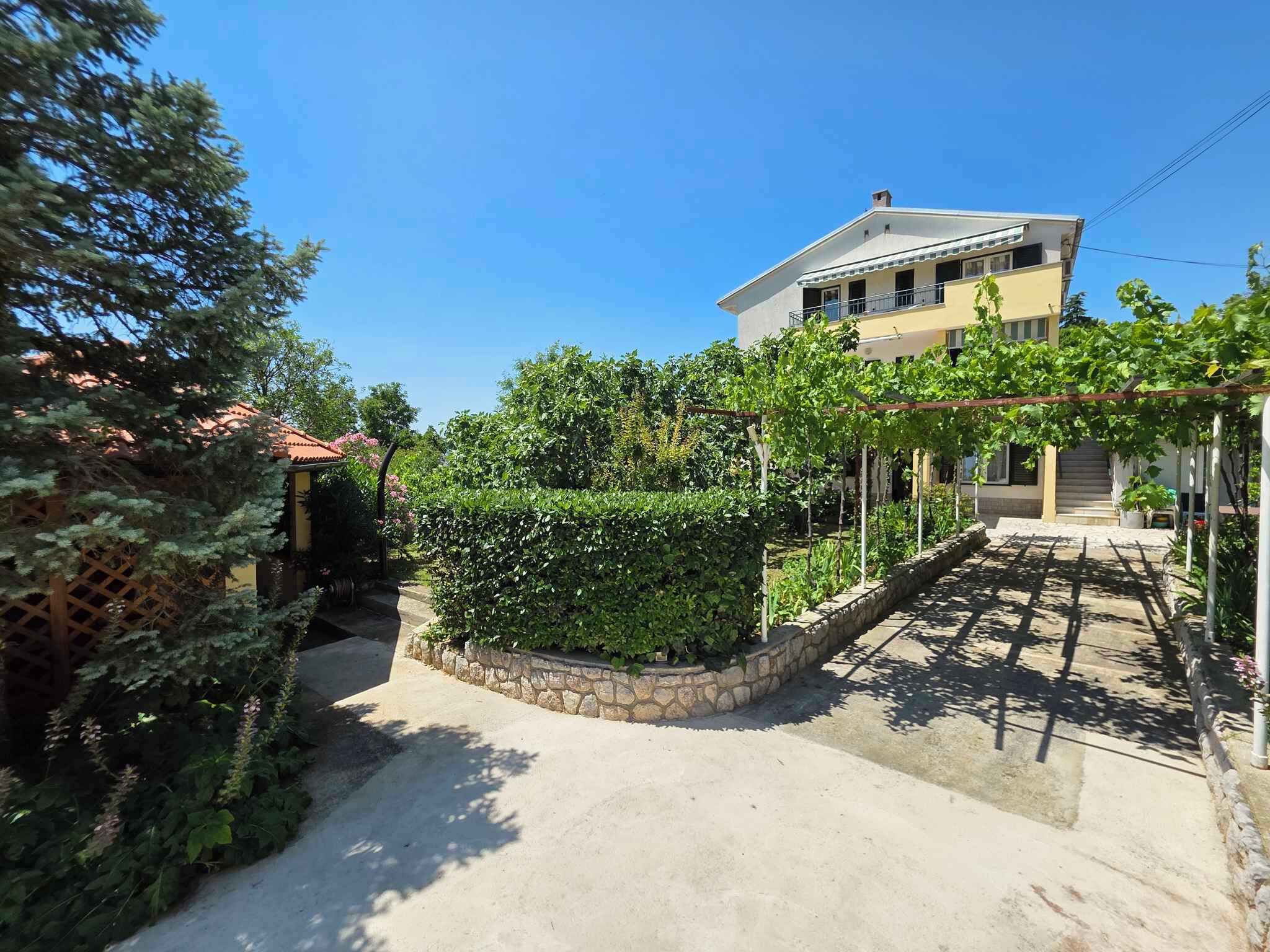 Un quartier résidentiel comprenant une maison, un chemin de pierre et un jardin agrémenté de diverses plantes et d’une pergola.