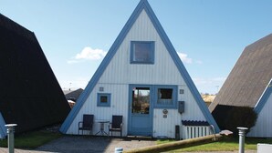 A triangular building with a blue door and windows, a small table, and two chairs outside. - 3 bedroom lovely home in Knebel (Knebel)