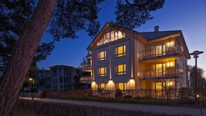 Un hotel de varios pisos con balcones, ventanas amplias y una fachada bien iluminada.