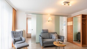 Una sala moderna con un sillón gris, un sofá gris y una mesa de centro de madera.