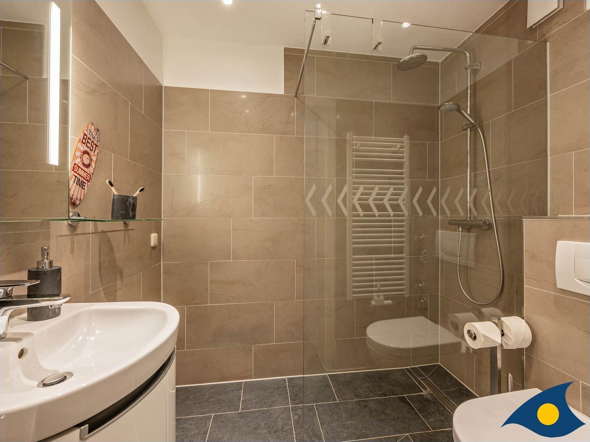 A modern bathroom with a glass-enclosed shower, a white sink, and a toilet.