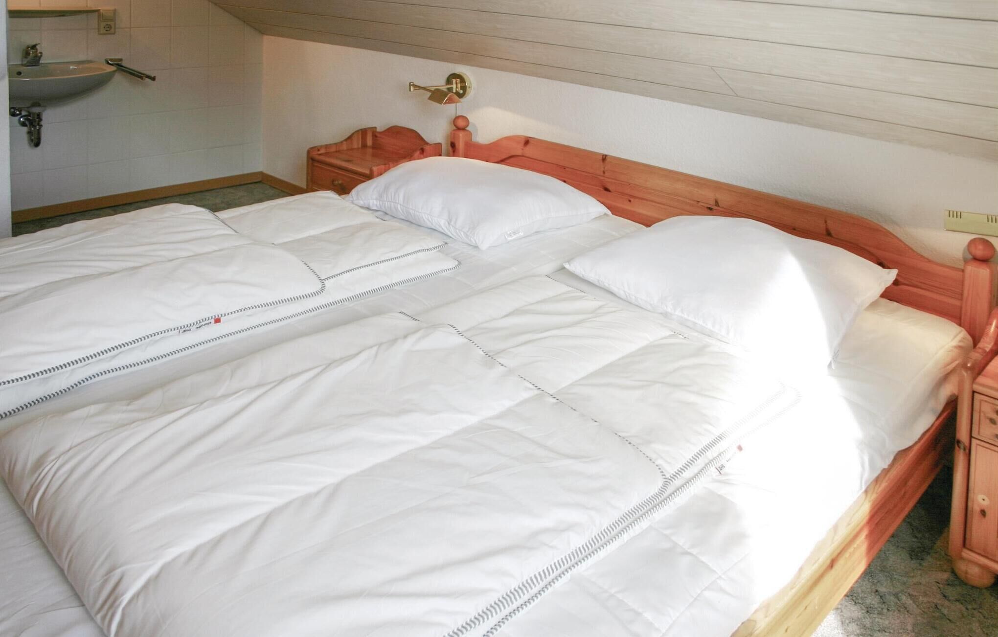Ein Doppelbett mit weißer Bettwäsche, einem hölzernen Kopfteil und einem Nachttisch.
