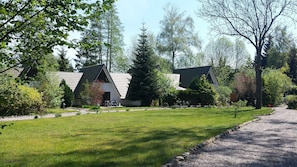 A row of modern, single-story cabins with sloped roofs, surrounded by a well-maintained lawn and trees.