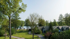 A lakeside lodge with a gravel path, a chair, and a building with a triangular roof.