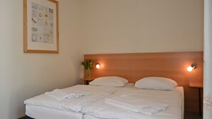 A hotel room with a large bed, two bedside tables, a wall-mounted light, and a framed picture on the wall. - FEWO 07 - Villa Celia Sellin (Sellin)