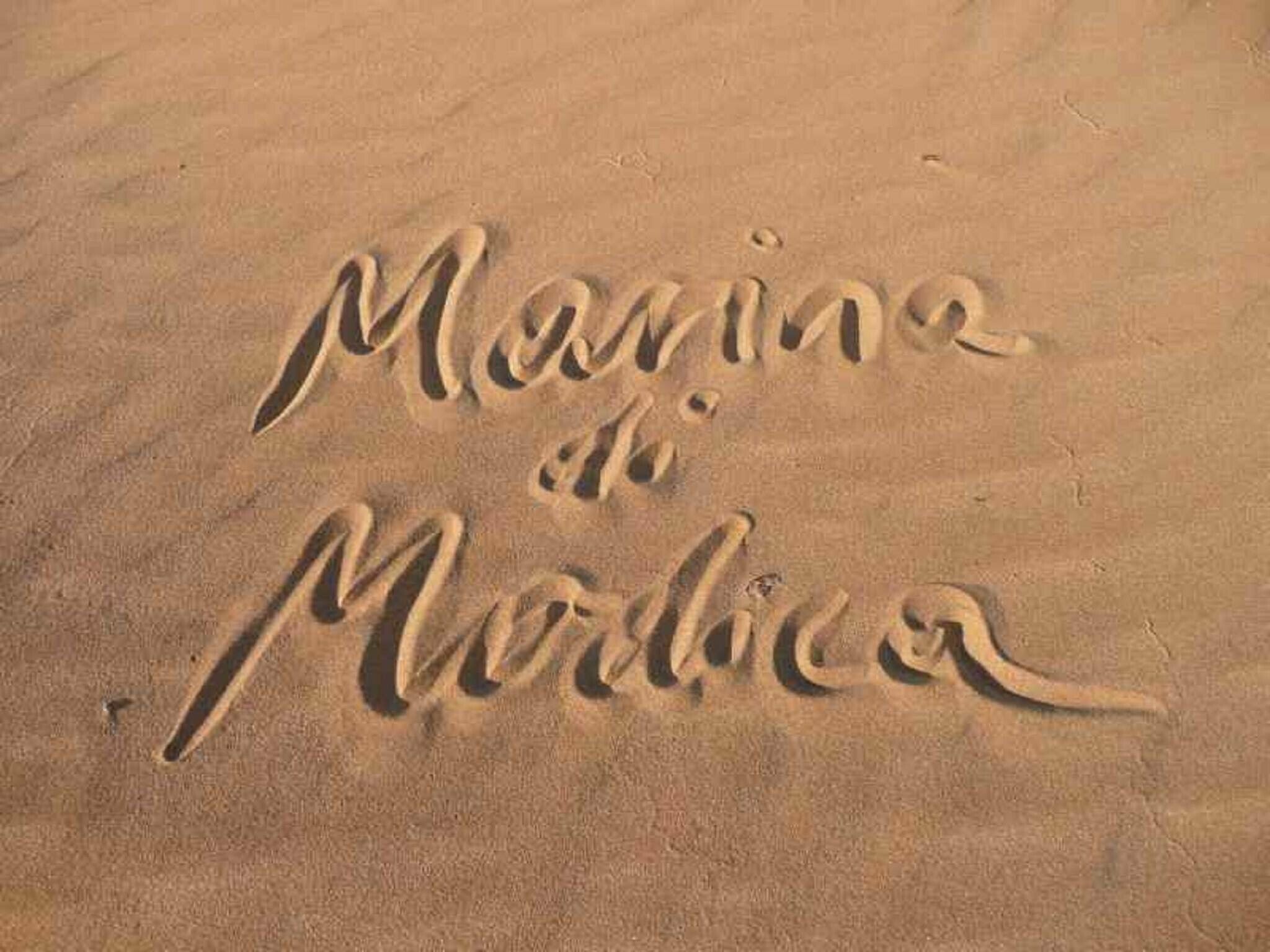 The word "Marina" written in the sand.