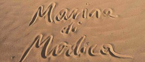 The word "Marina" written in the sand.