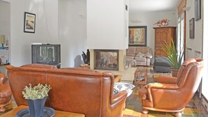 Una sala de estar con chimenea, sofás de cuero, televisor y un ventanal grande.