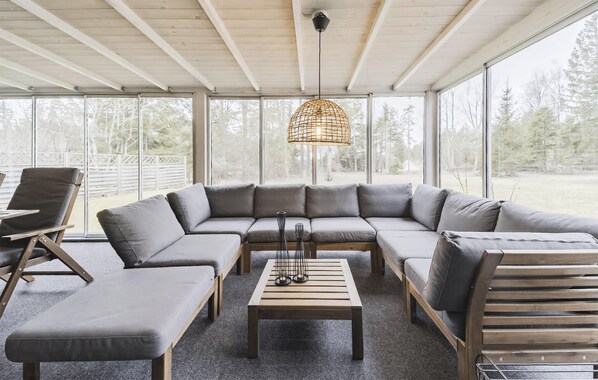 A covered outdoor seating area with a sectional sofa, two chairs, a coffee table, and a hanging light fixture. - 2 bedroom stunning home in Slite (Slite)