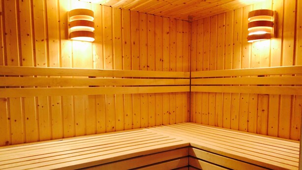 A sauna with wooden walls and benches, equipped with wall-mounted lights. - Villa Sun 4, 2-5 P. Terrace - Villa Sun Terrace, Nicole Struck (Neustadt in Holstein)