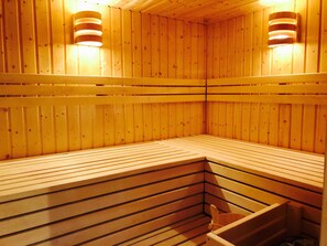 Sauna, jossa on puuseinät ja -lauteet sekä seinään kiinnitetyt valaisimet.
